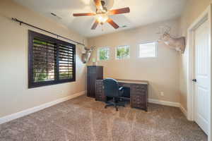 Carpeted office space featuring baseboards and ceiling fan