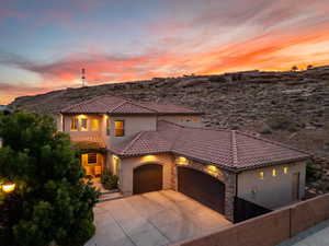 Mediterranean / spanish house featuring a garage, stucco siding, concrete driveway, stone siding, and a tiled roof