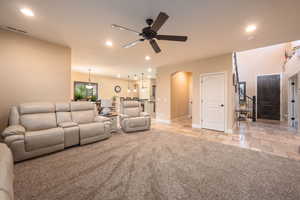 Living room featuring light carpet, recessed lighting, arched walkways, stone tile flooring, and a ceiling fan