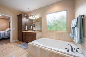 Bathroom featuring ensuite bath, vanity, a whirlpool tub, and wood finish floors