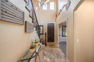 Entryway featuring a high ceiling, stone tile floors, a chandelier, and arched walkways