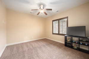 Carpeted empty room featuring baseboards and a ceiling fan
