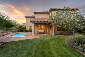 Rear view of property with a lawn, a patio area, stucco siding, and an outdoor pool