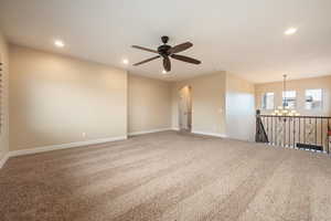 Empty room with arched walkways, carpet, recessed lighting, a chandelier, and ceiling fan