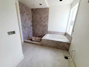 Bathroom featuring a bath, tiled shower, and tile walls