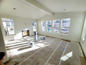 Unfurnished living room with healthy amount of natural light and beamed ceiling