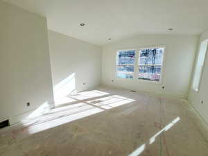 Unfurnished room featuring vaulted ceiling and baseboards