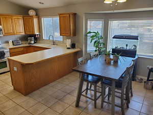 Kitchen with light countertops, range with two ovens, brown cabinetry, and a peninsula