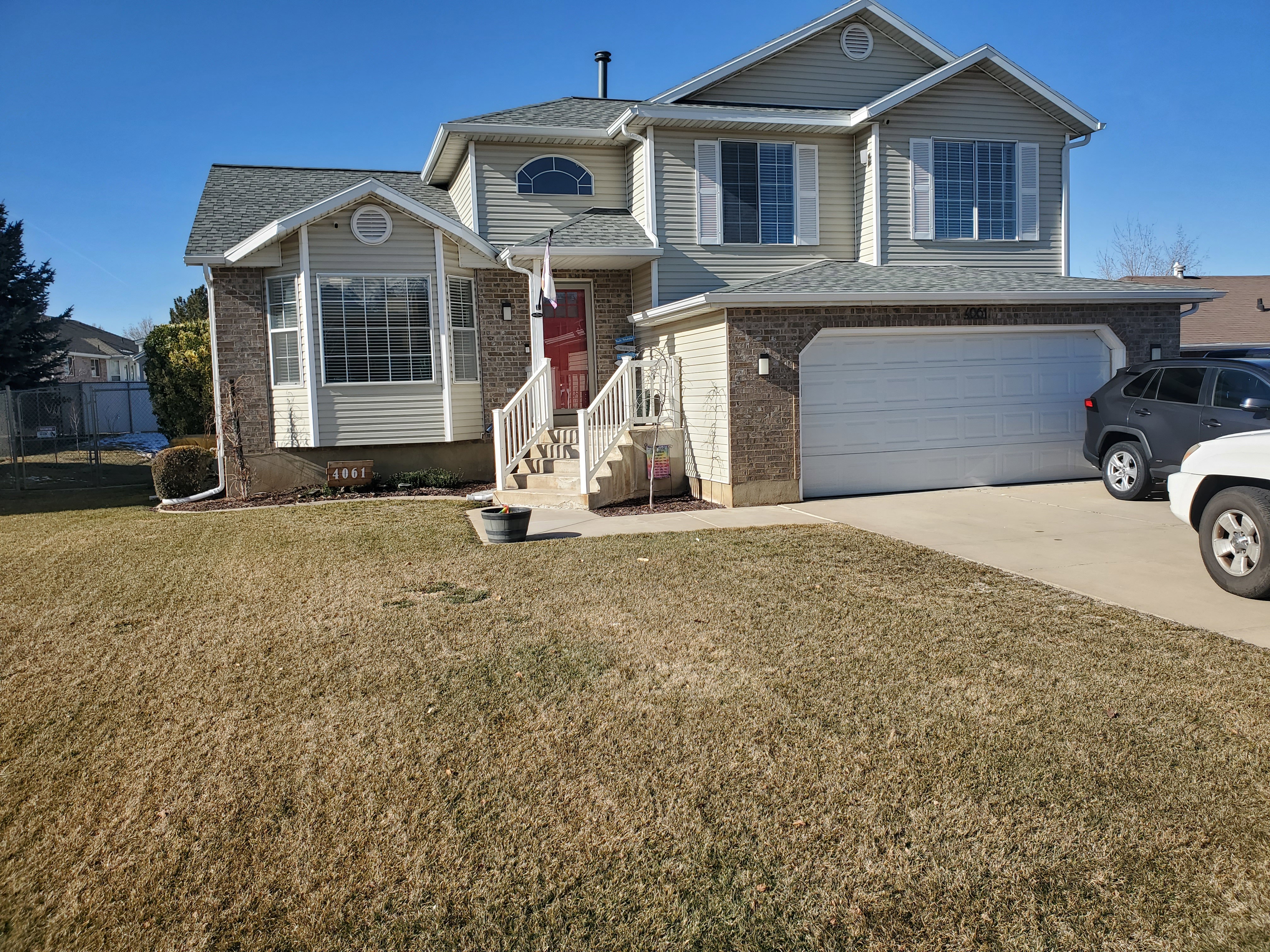 Tri-level home featuring an attached garage, concrete driveway, brick siding, and roof with shingles