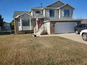 Tri-level home featuring an attached garage, concrete driveway, brick siding, and roof with shingles