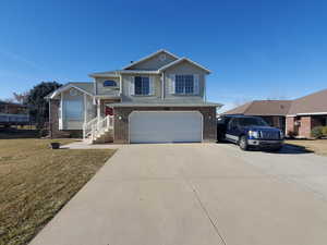 View of front of property with a garage, brick siding, and driveway