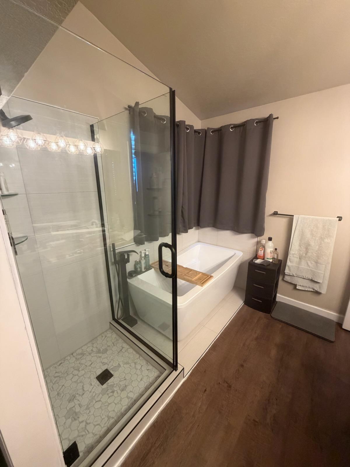 Full bath featuring a shower stall, a garden tub, dark wood-style floors, and vaulted ceiling
