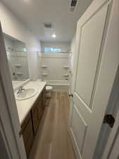 Full bath featuring bathing tub / shower combination, vanity, and light wood-style flooring