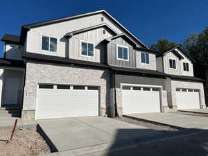 View of front facade with stone siding, driveway, and a garage