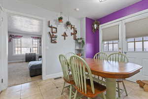 Dining area featuring plenty of natural light, a textured ceiling, light tile patterned flooring, and light carpet