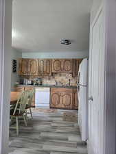 Kitchen featuring wood finish cabinets, decorative backsplash, white appliances.