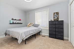 Bedroom with light colored carpet and a closet