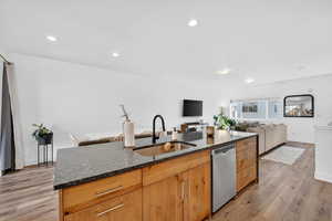 Kitchen featuring dark stone counters, light wood-style floors, open floor plan, stainless steel dishwasher, and recessed lighting