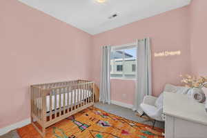 Bedroom featuring a nursery area and light carpet