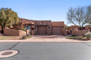 Adobe home featuring a gate, stone siding, a fenced front yard, and driveway