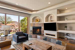 Living room with a fireplace, built in shelves, and recessed lighting