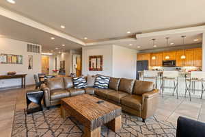 Living room featuring recessed lighting, light tile patterned floors, and a tray ceiling