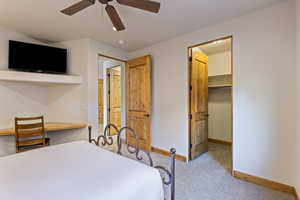 Bedroom with built in desk, light colored carpet, a spacious closet, and ceiling fan