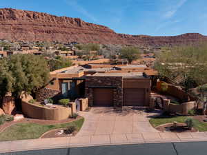 View of front of house with stucco siding, a mountain view, driveway, a garage, and a patio area