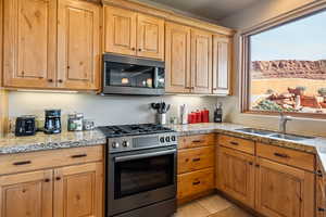 Kitchen featuring stainless steel appliances, light stone countertops, and light tile patterned floors