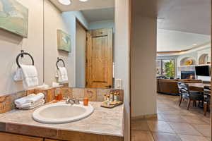 Bathroom with vanity, recessed lighting, a tile fireplace, and tile patterned floors