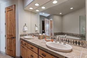 Bathroom featuring double vanity, a bath, and recessed lighting