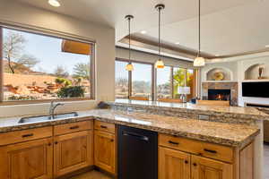 Kitchen with dishwasher, decorative light fixtures, a tile fireplace, open floor plan, and recessed lighting