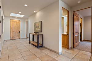 Hallway featuring a skylight, light tile patterned flooring, and recessed lighting