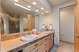 Full bathroom with double vanity, a shower stall, light tile patterned floors, and recessed lighting