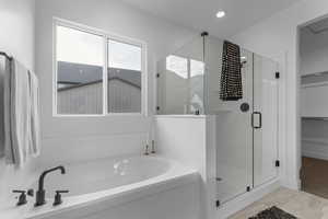 Bathroom with a shower stall, a bath, a walk in closet, and recessed lighting