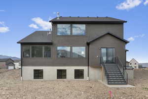 Back of property featuring stucco siding, stairway, roof with shingles, and a mountain view