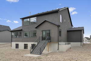 Back of house with stucco siding and stairs