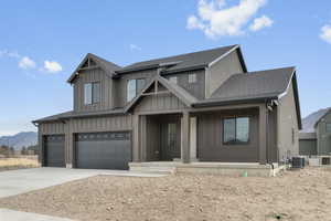 View of front of house with board and batten siding, a shingled roof, covered porch, a mountain view, and driveway