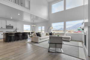 Living area featuring a chandelier, a mountain view, a fireplace, light wood-style floors, and a towering ceiling