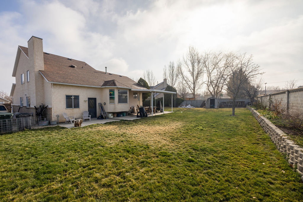Rear view of house with a fenced backyard, a patio, a chimney, and stucco siding
