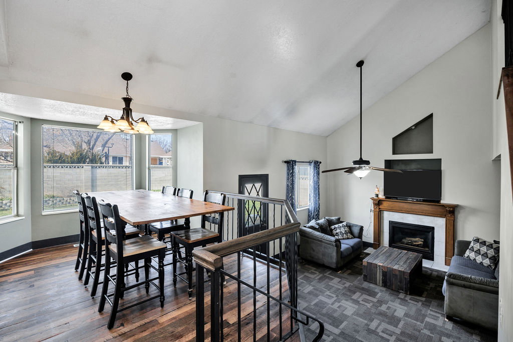 Dining area with a fireplace, dark wood-style flooring, a chandelier, and high vaulted ceiling