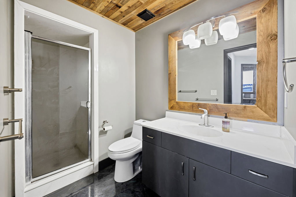Bathroom featuring a stall shower, wooden ceiling, and vanity