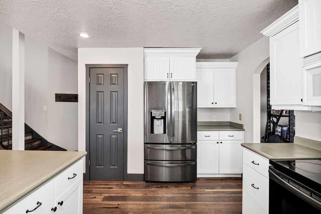 Kitchen featuring stainless steel fridge, a textured ceiling, white cabinetry, black electric range oven, and dark wood-type flooring