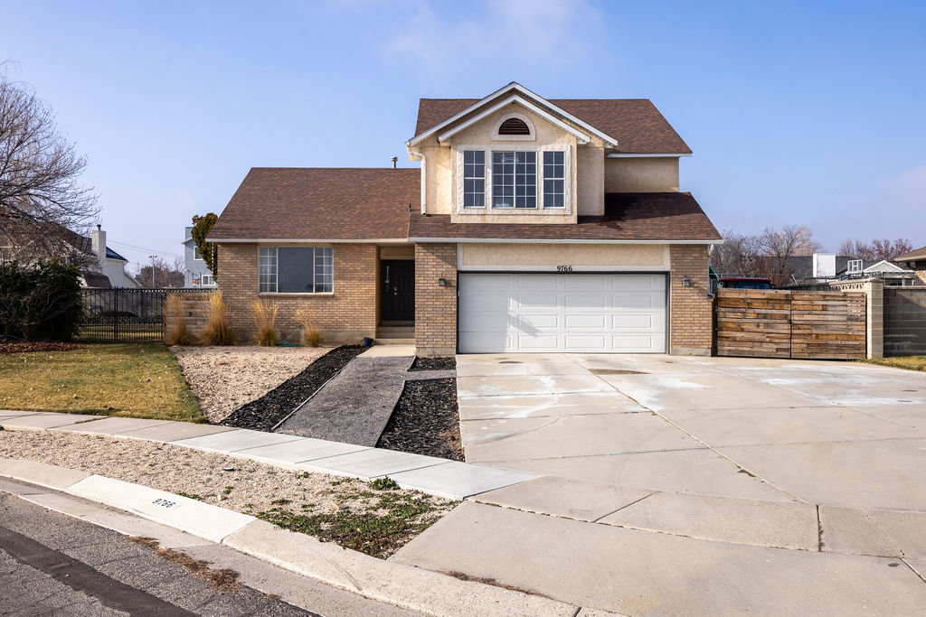Traditional-style house with a shingled roof, concrete driveway, an attached garage, and brick siding