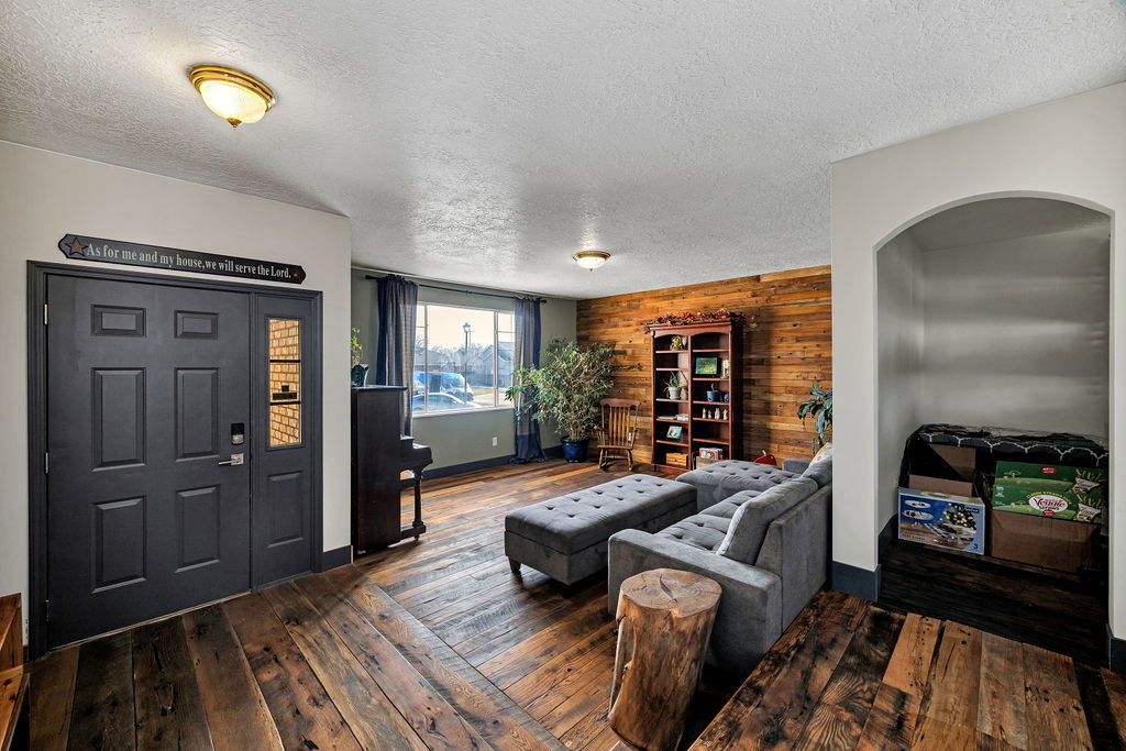Living area with a textured ceiling, dark wood finished floors, and wooden walls