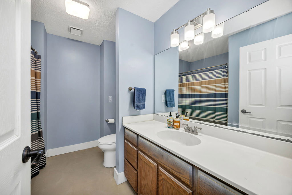 Full bathroom with curtained shower, vanity, and a textured ceiling