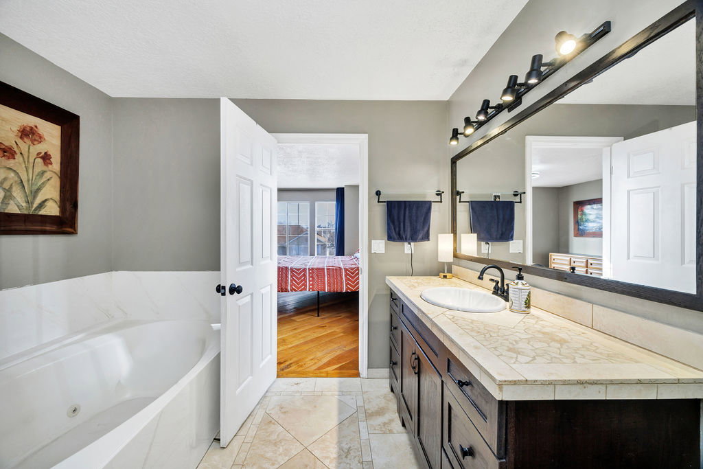 Ensuite bathroom featuring vanity and a jetted bath