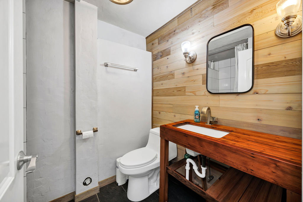 Three-quarter bathroom featuring wooden walls and vanity