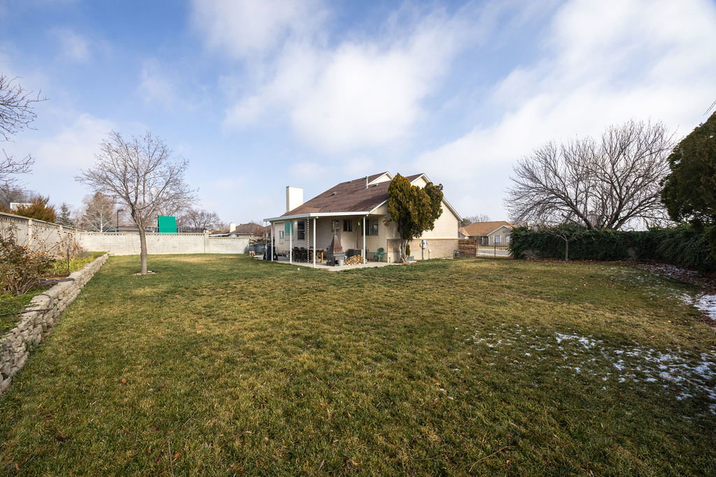 Rear view of property featuring a patio area, a fenced backyard, and a chimney