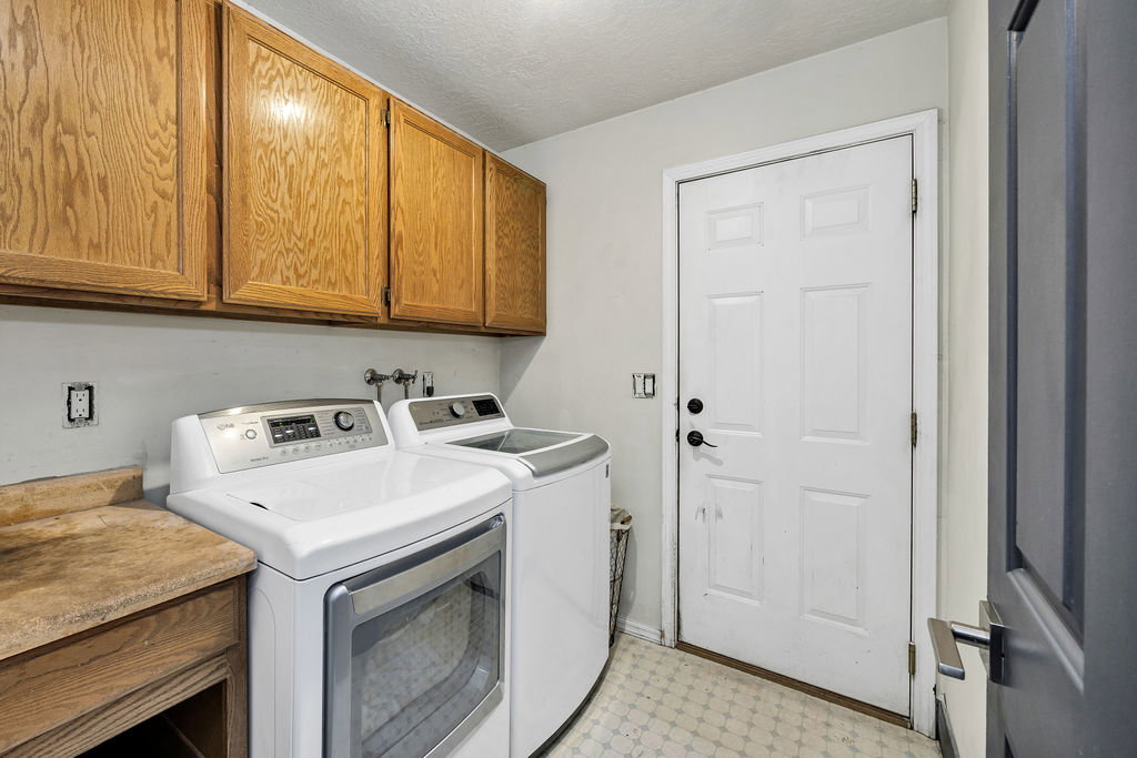 Washroom with light flooring, washer and dryer, cabinet space, and a textured ceiling